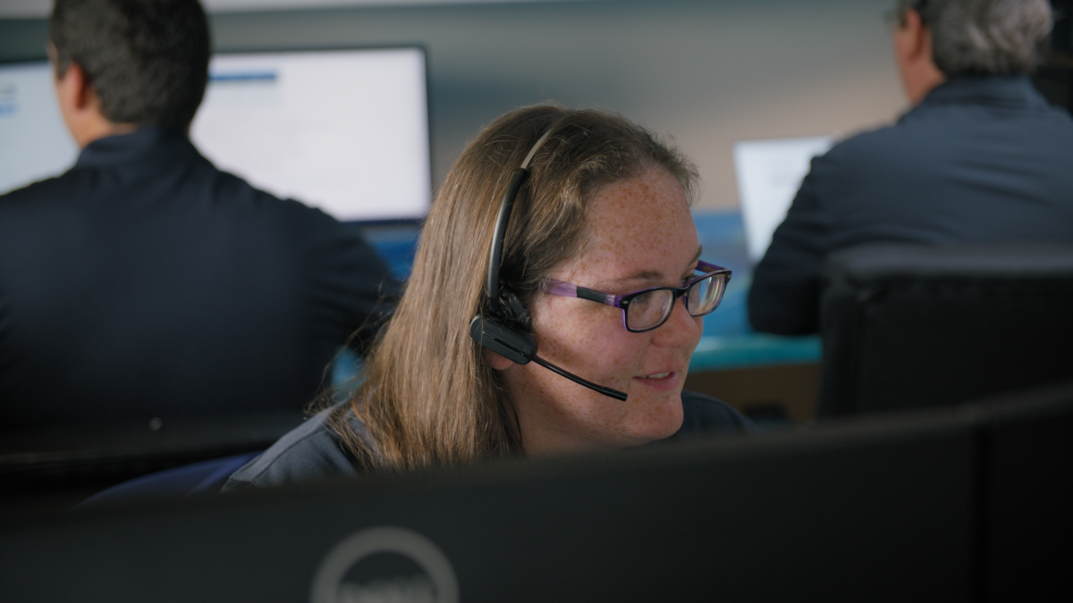 A Customer Care Specialist speaks with a customer over the phone while wearing a headset.